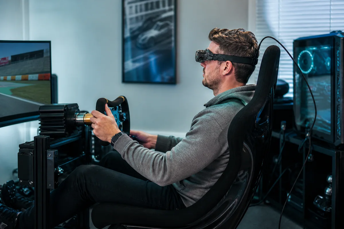 PC sim racer wearing an ultra-light tethered VR headset in a racing cockpit