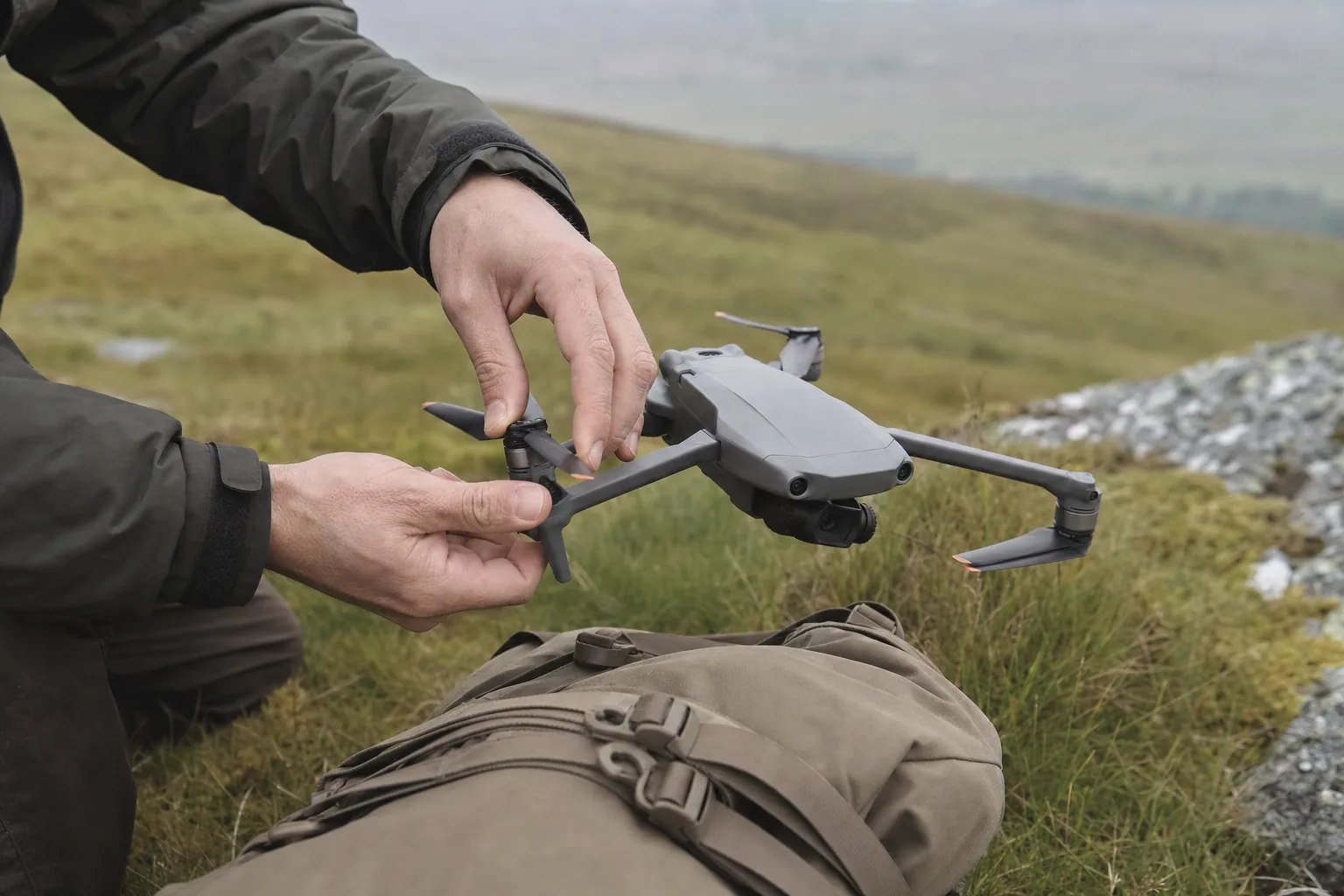 Unfolding the DJI Mini 5 Pro's arms in a field before flight