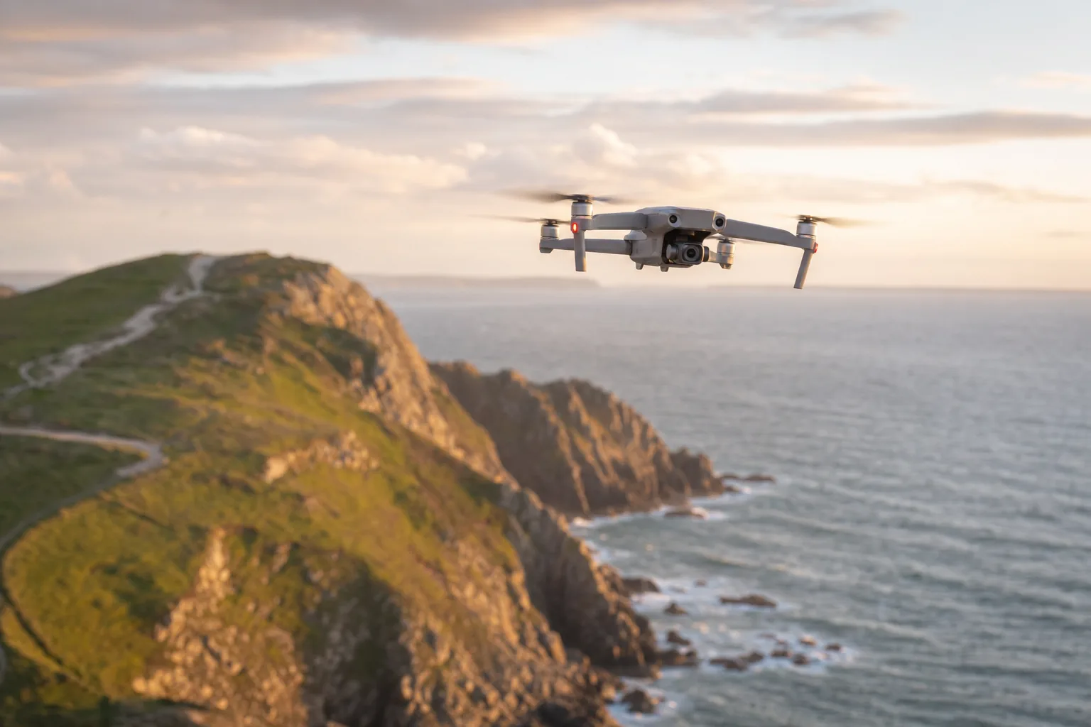 DJI Mini 5 Pro flying over a British coastal headland at golden hour