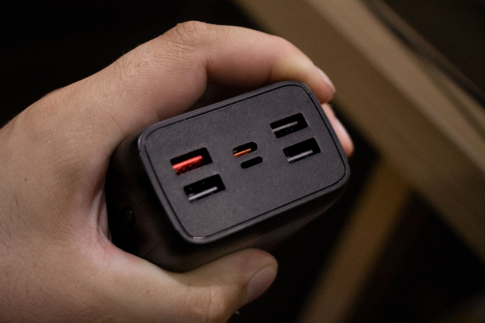 GaN Charger In Use image of Someone holding or plugging in the Baseus GaN 100W charger, showing its small size relative to the hand or outlet