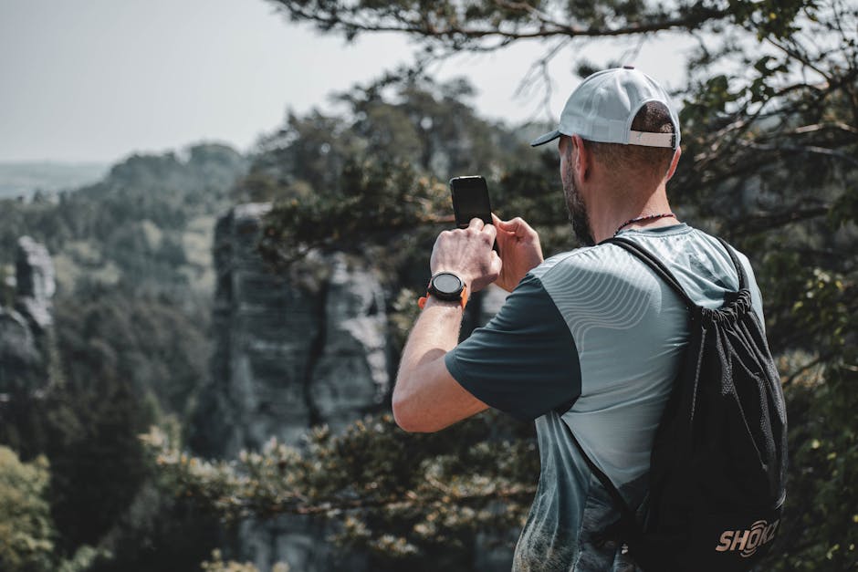 A man captures the beauty of Czech nature with his smartphone while hiking outdoors.