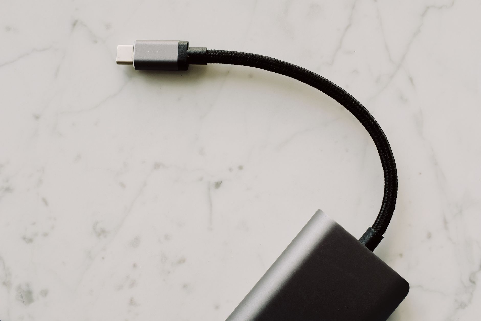 Hero image of Clean product photo of a USB-C cable coiled or laid flat on a neutral surface, clearly showing both connectors and cable build quality
