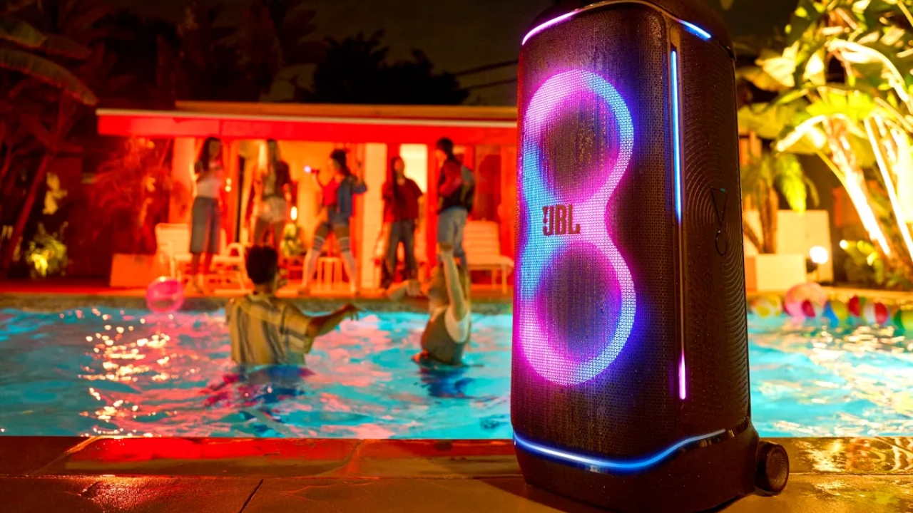 JBL PartyBox 720 lit up at a night-time pool party with the dual-woofer LED pattern glowing