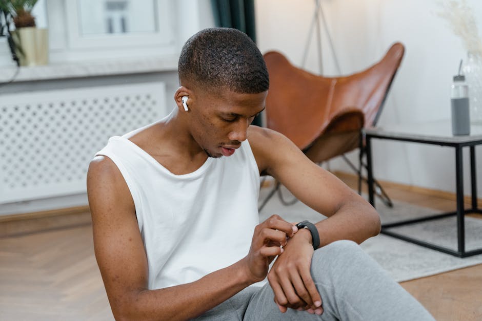 A man indoors uses a smartwatch for monitoring workouts, wearing AirPods.