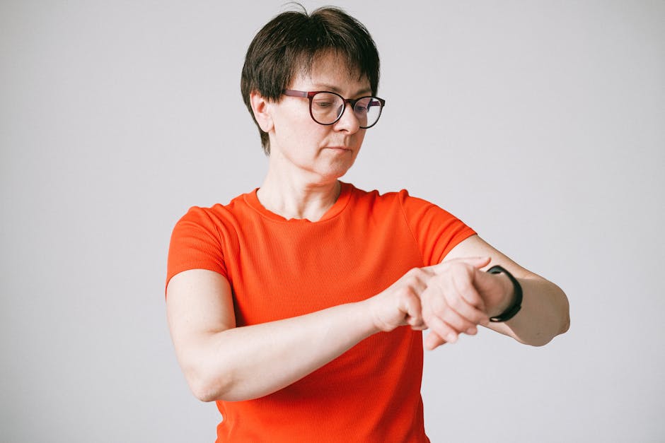 A woman in glasses checks her smartwatch in a minimalist indoor setting.